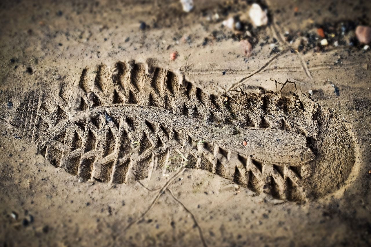 Descubre dónde trabaja un forense y cuáles son sus funciones en el campo de la medicina legal: huella de bota con patrón profundo en arena
