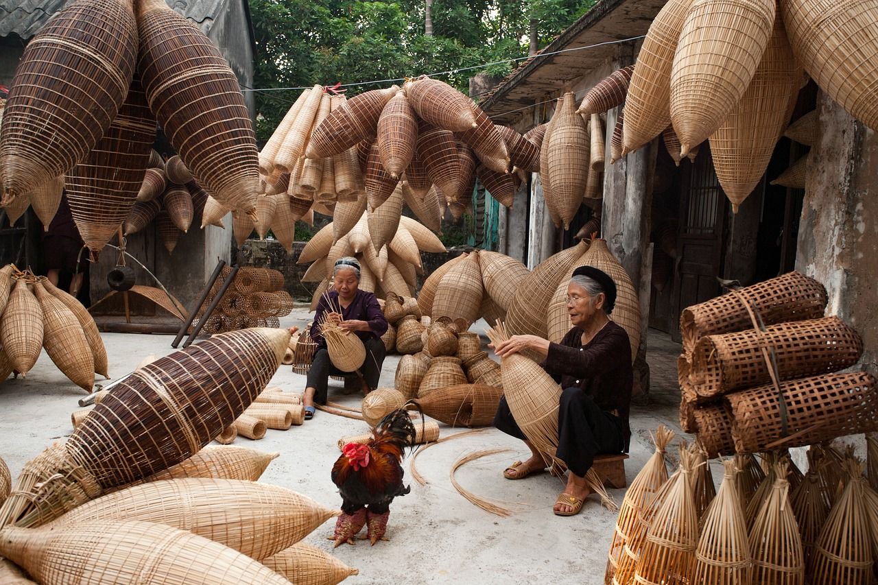 Dos mujeres mayores tejiendo cestas y trampas de mimbre en un patio-taller, Descubre dónde trabajan los artesanos y cómo influye en su creatividad