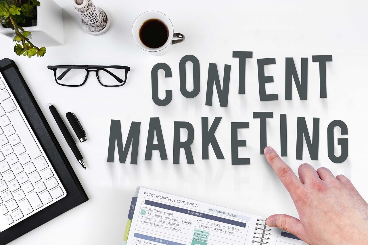 Descubre dónde trabajan los escritores y encuentra tu inspiración laboral en un escritorio organizado con teclado, gafas, cuaderno, café y la frase CONTENT MARKETING.